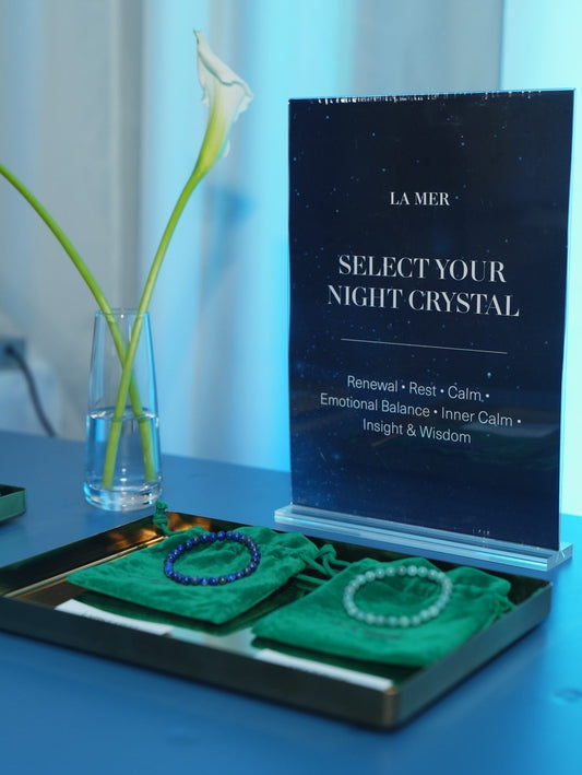 Custom crystal bracelet corporate giveaways by Made by KCA for La Mer’s Nights of Renewal, displayed on green velvet pouches with elegant blue lighting