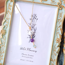 Necklace with floral design and purple bead in a decorative photo frame