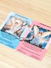 Two printed oracle-style cards laid on a light wood surface, each featuring an angel illustration and text. A beaded bracelet with clear beads and silver-toned links is draped across both cards.