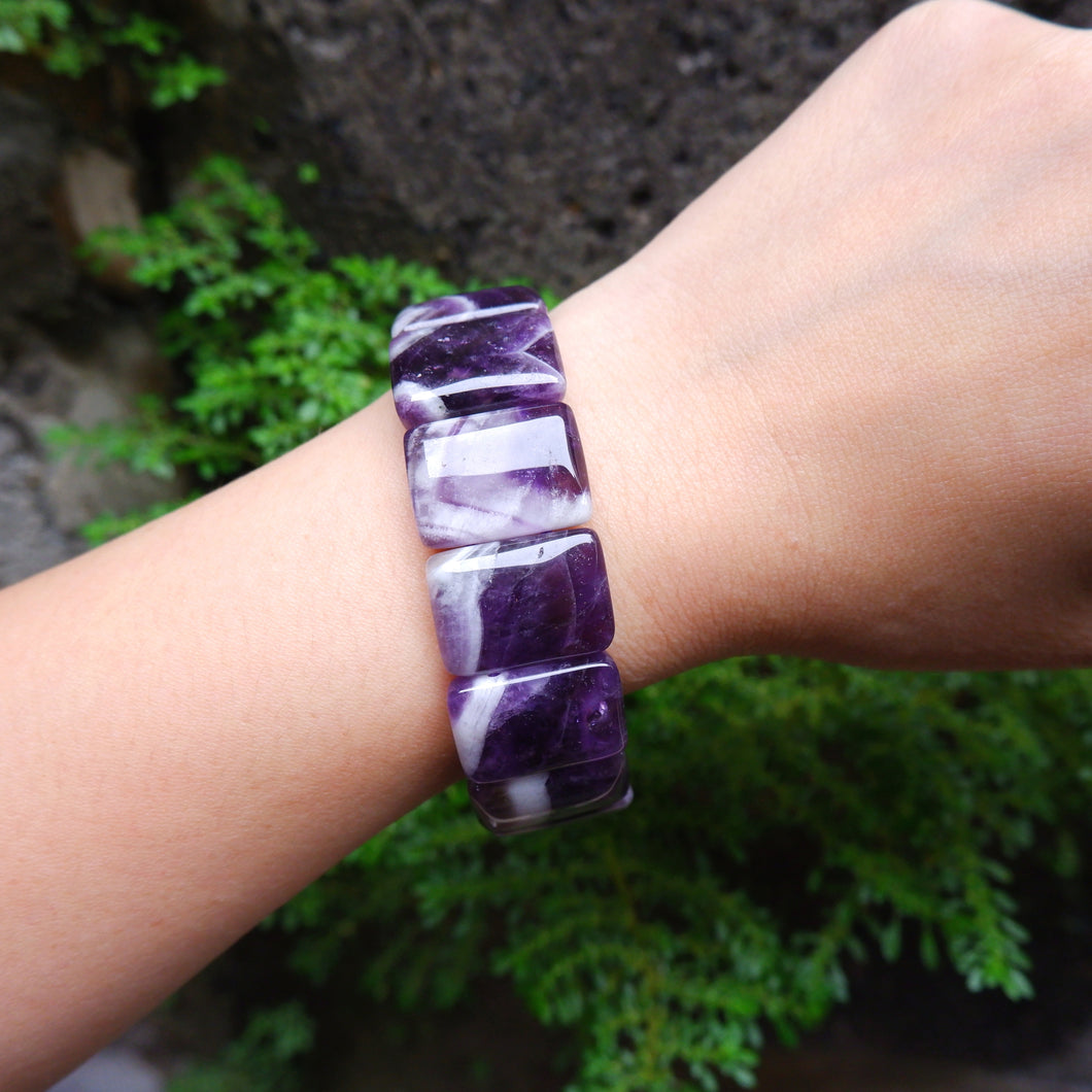 Purple and white striped bracelet on a wrist with a natural background