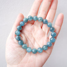 Blue green kyanite handmade beaded bracelet on a hand against a light gray background