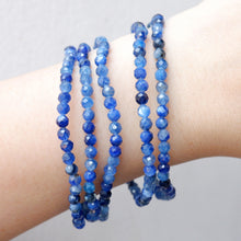 Five blue beaded bracelets on a wrist against a light background