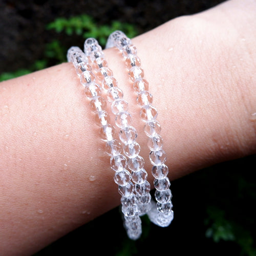 Three handmade clear beaded bracelets on a wrist with a natural background