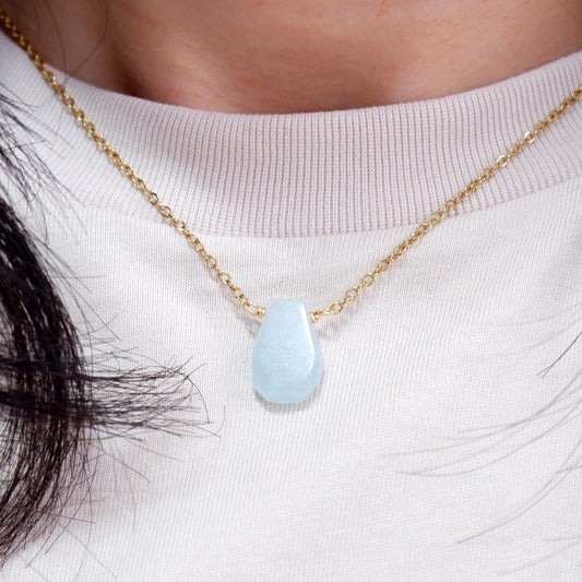 Necklace with a light blue teardrop pendant on a white background