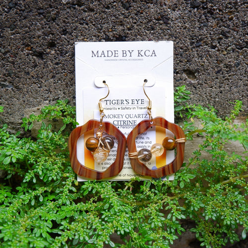 Pair of earrings on a card labeled 'Made by KCA' with a natural background