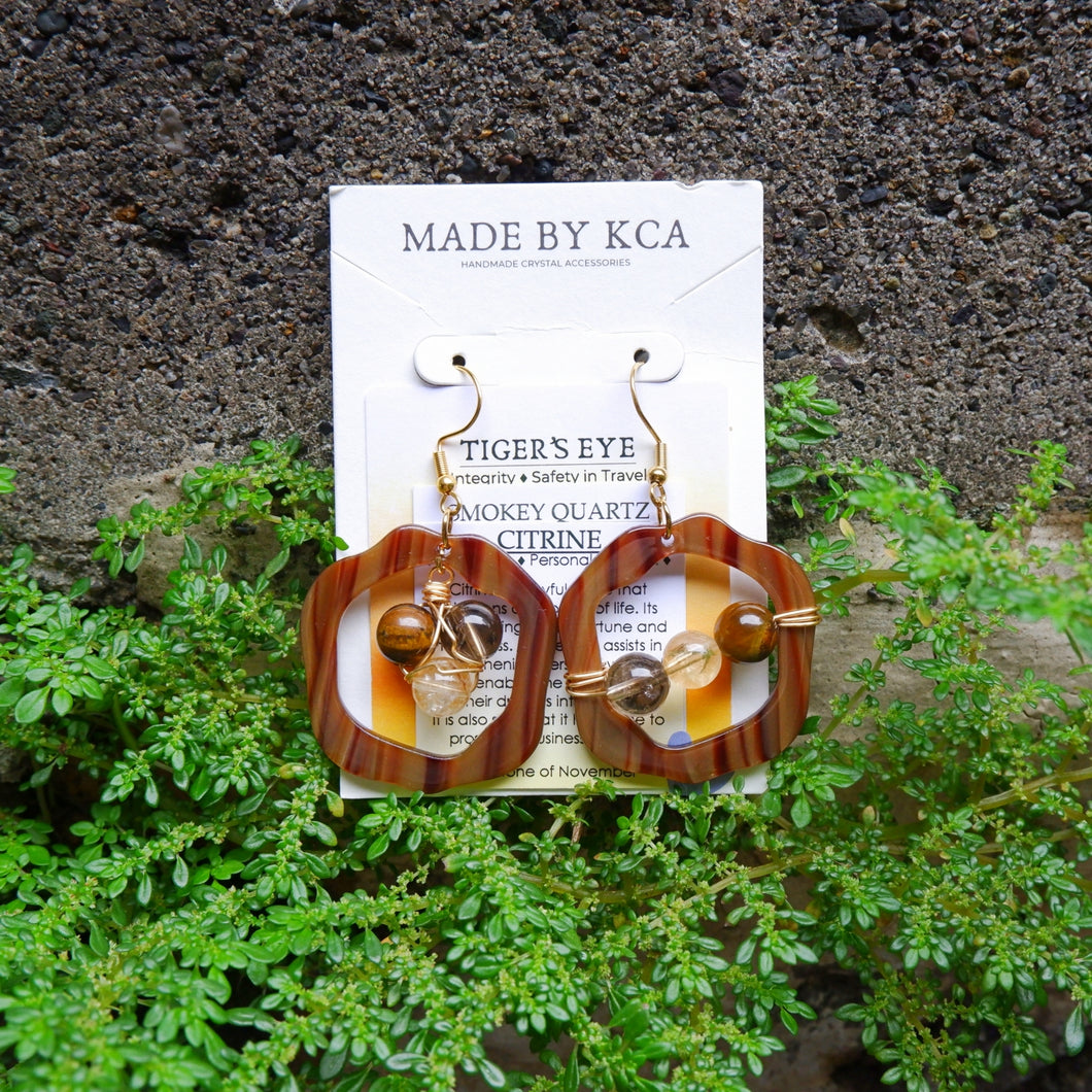 Pair of earrings on a card labeled 'Made by KCA' with a natural background