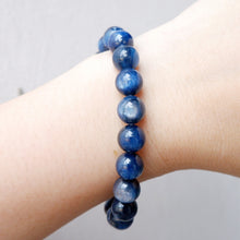 Blue natural crystal beaded bracelet on a wrist against a neutral background