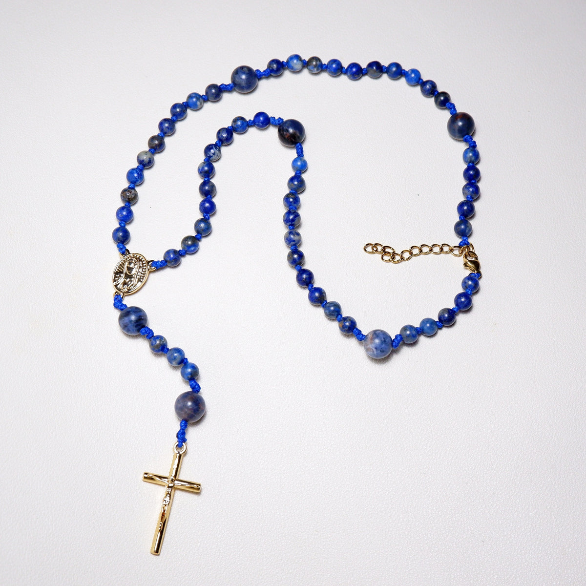 Blue beaded rosary necklace with a gold cross on a white background