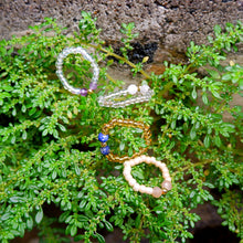 Four beaded bracelets on a green leafy background