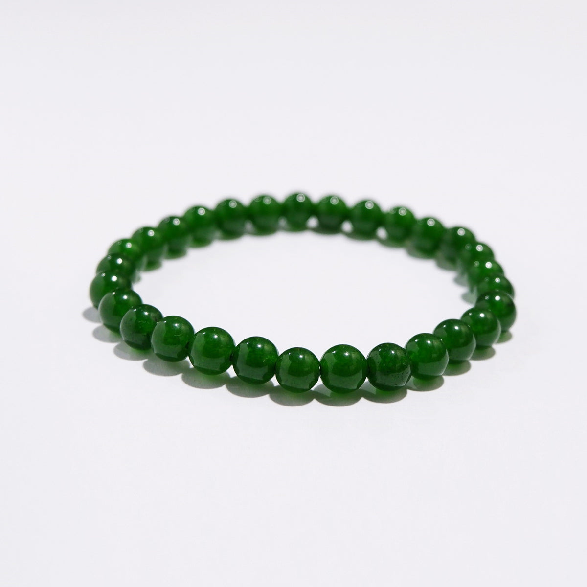 A green aventurine bracelet with a series of round beads strung together on a white background.