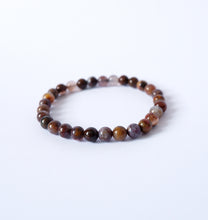 A bracelet made of polished Pietersite crystal beads, strung together with a durable garter, displayed against a white background.