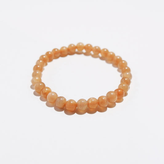 lose-up of Sunstone beads showing natural white and black specks, subtle streaks, and variations in warm orange hue